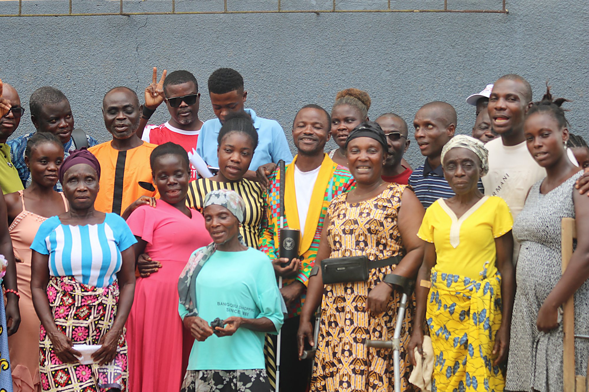 A large group of persons with disabilities standing together for a photograph, several holding crutches and white canes.