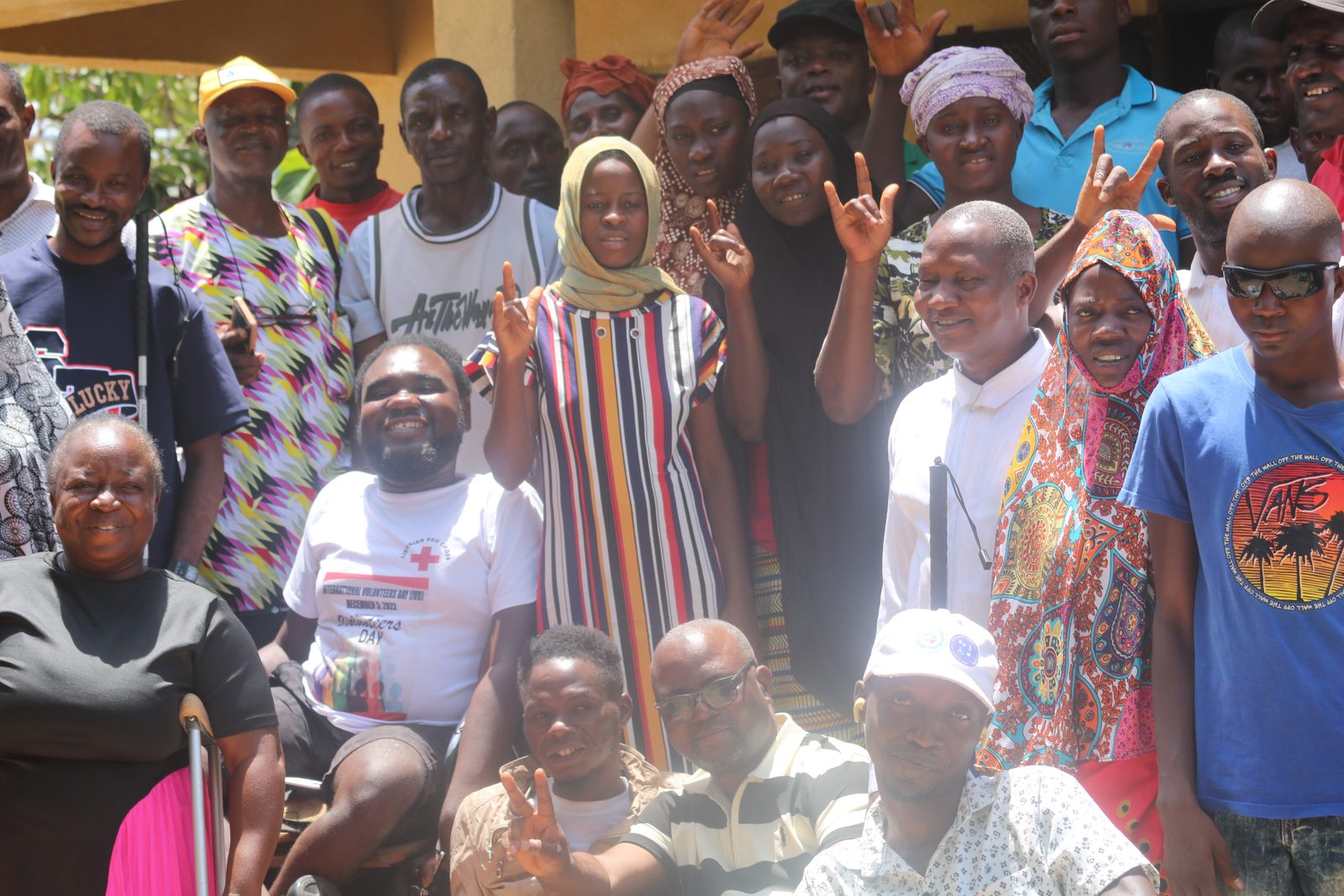 Persons with disabilities and Commission staff gathered together at a community meeting, several raising their hands.