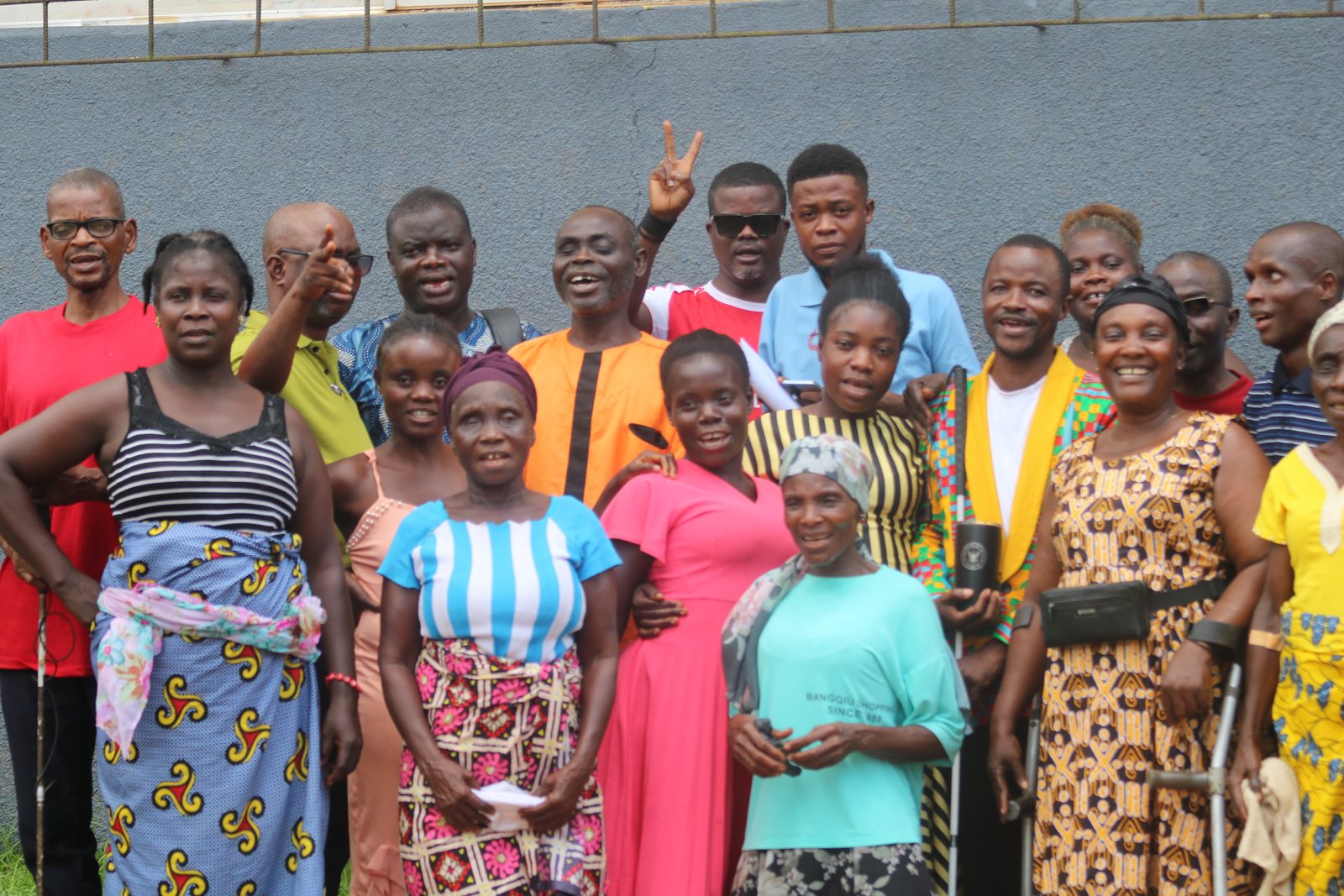 A group of persons with visual disabilities standing together, several holding white canes.