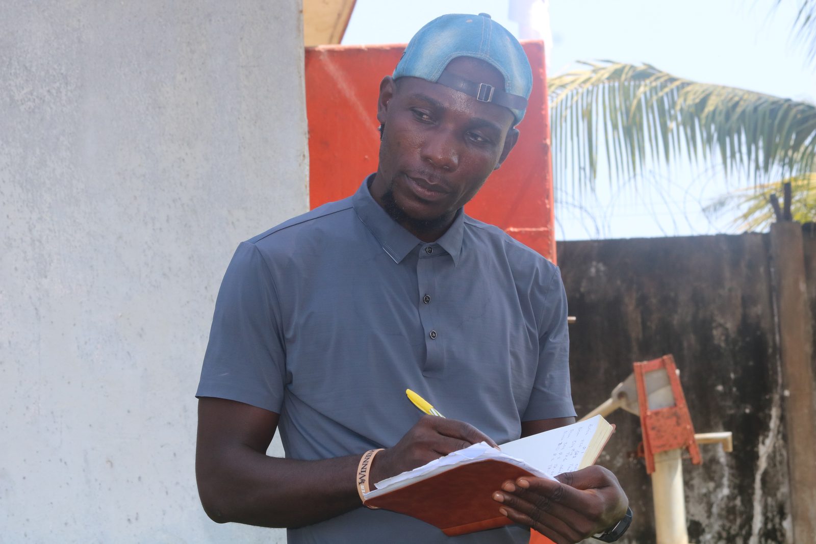 A young man writing in a notebook while recording details during a community assessment.
