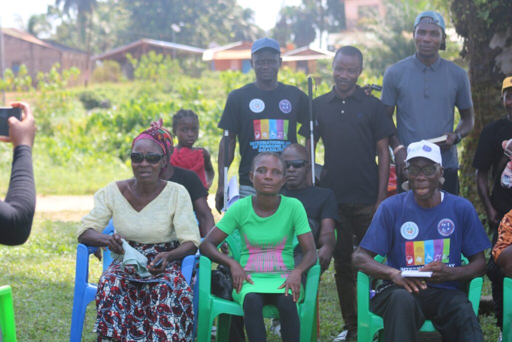 Community members, including a wheelchair user, seated together with Commission staff during a county visit.