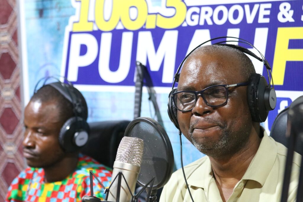 Two men wearing headphones speak into studio microphones during a radio discussion.