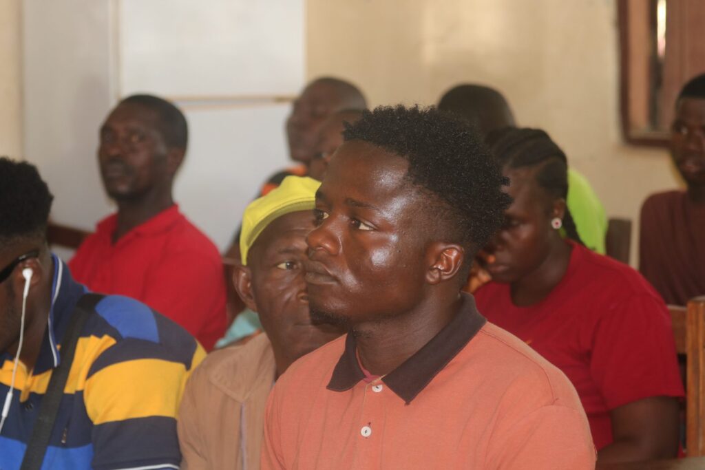 Participants seated at desks in a hall during a community session.